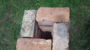 Looking down on the half-way-built rocket stove. the bricks make the shape of a large square with a smaller square in the middle for the chimney hole.