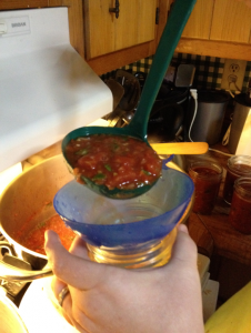 Preparing the homemade salsa for canning by pouring the salsa into a jar.