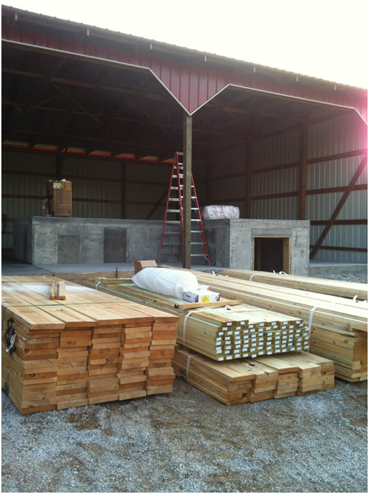 large stacks of lumber lying in front of the tractor shed for the shed house conversion