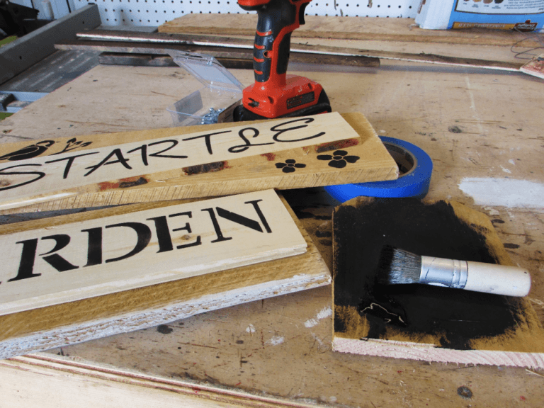 Wooden signs next to a paint brush used for stenciling.