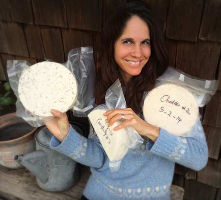 Corina Sahlin holding three sealed wheels of homemade cheese